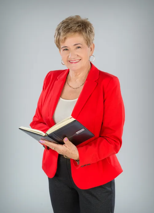 Właścicielka firmy - uśmiechnięta Alicja Czykiejda w czerwonym żakiecie, trzymająca kalendarz.